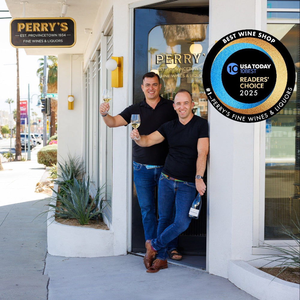 Two men standing outside a building with 'Perry's' signage and an award on a sunny street.